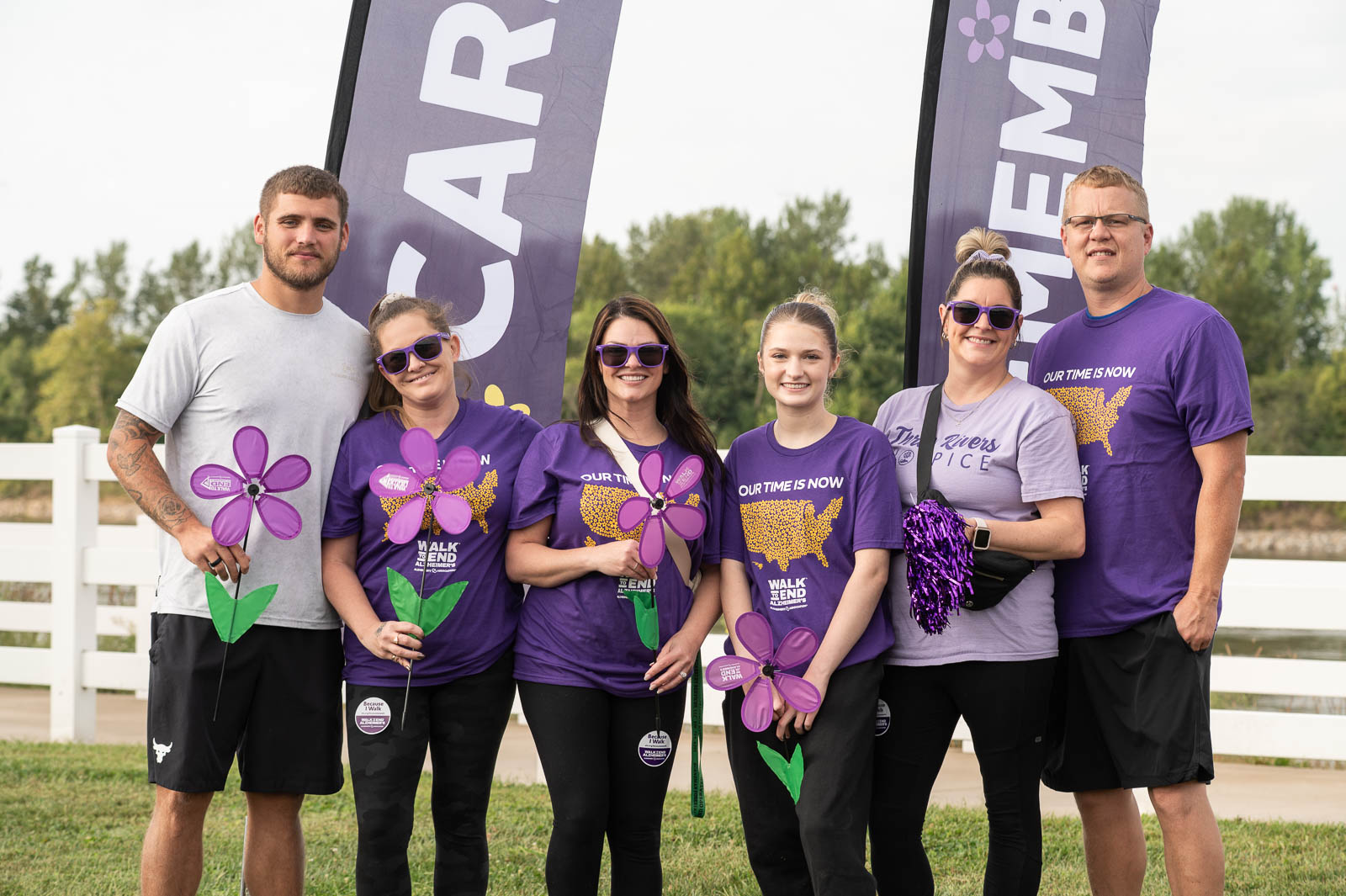 Family group wearing purple shirts and holding purple flowers in front of event banners at the Walk to End Alzheimer’s in St. Joseph, Missouri.