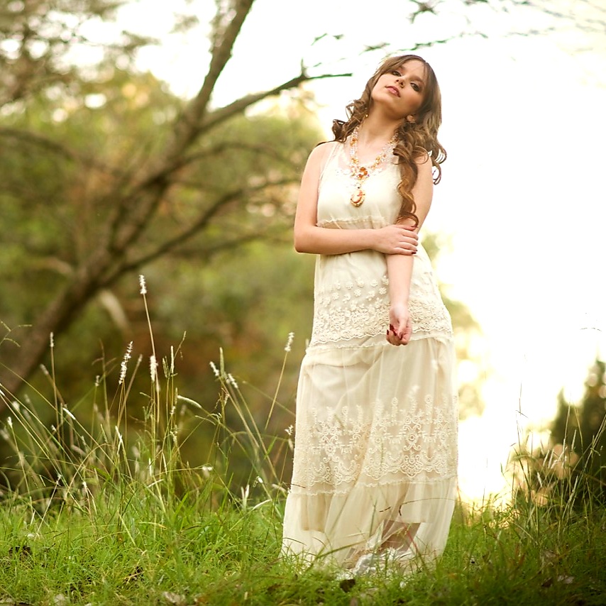 Young woman in a white dress posing outdoors in a natural autumn setting in St. Joseph, Missouri.